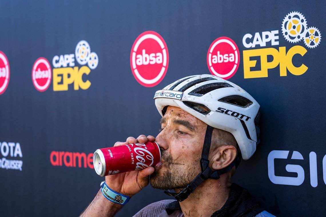 Nino Schurter enjoying Coke after taking the stage win on a hot and dusty Stage 1 of the 2025 Absa Cape Epic Mountain Bike stage race held at Meerendal Wine Estate, Cape Town, South Africa on the 17th March 2025. Photo by Dom Barnardt/Cape Epic
PLEAS