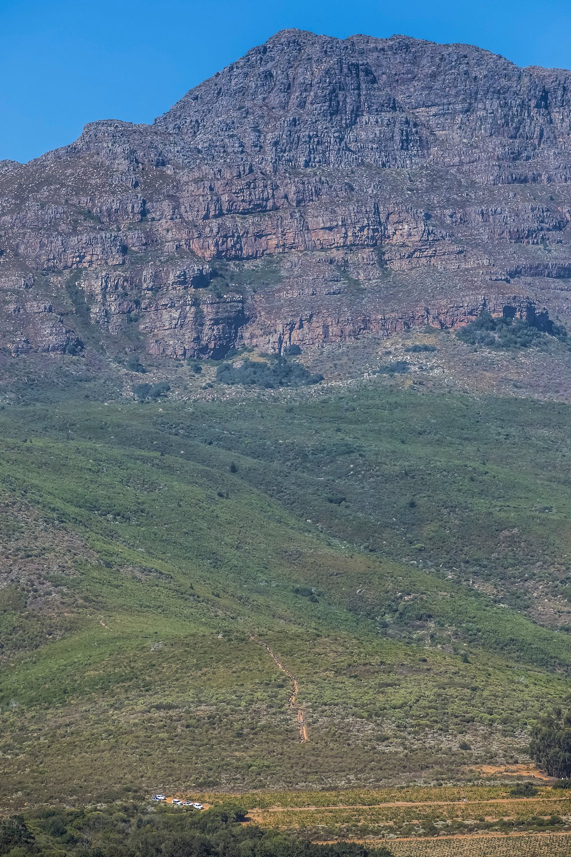 The massive climb of the day can be seen at the bottom of the Helderberg mountain during stage 1 of the 2022 Absa Cape Epic Mountain Bike stage race from Lourensford Wine Estate to Lourensford Wine Estate, South Africa on the 21st March 2022. © Dom B