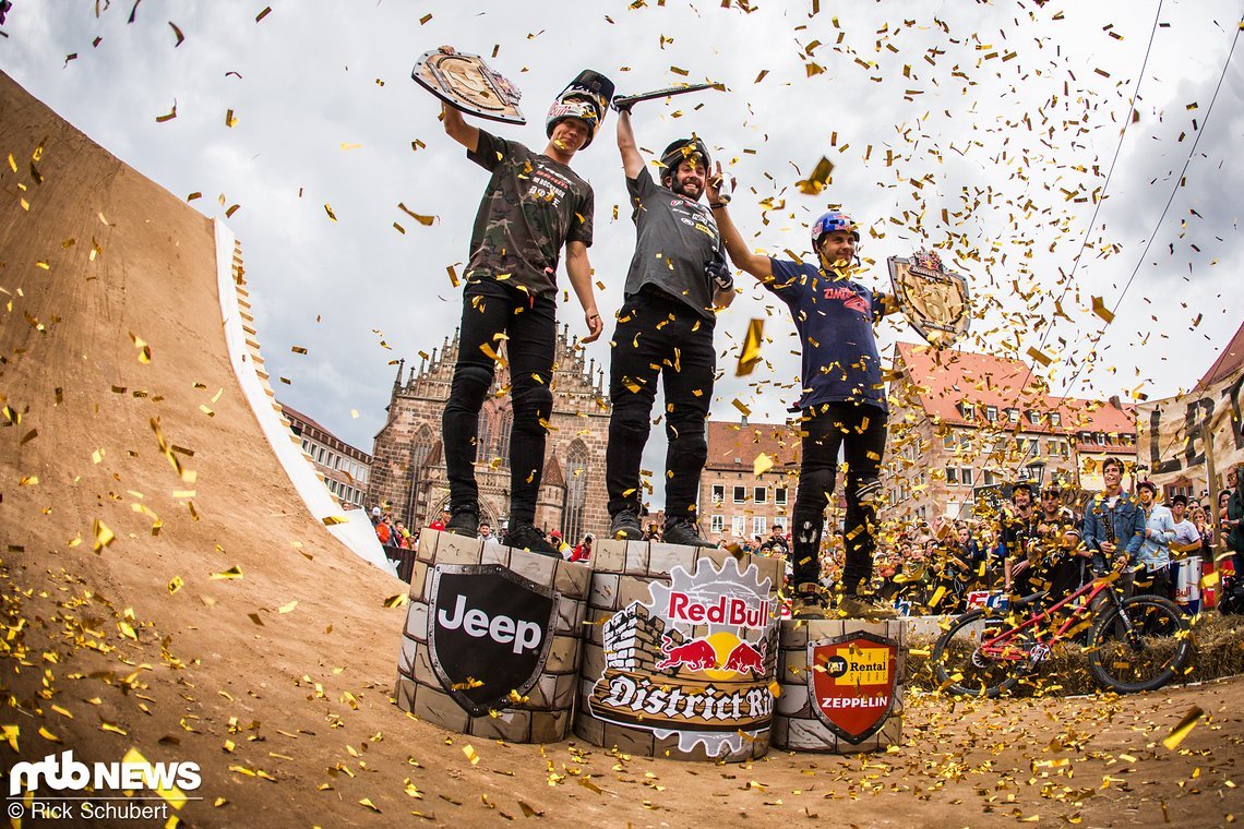 Emil Johansson, Nicholi Rogatkin und Szymon Godziek feiern unter Goldregen die Siegerehrung des Red Bull District Ride 2017