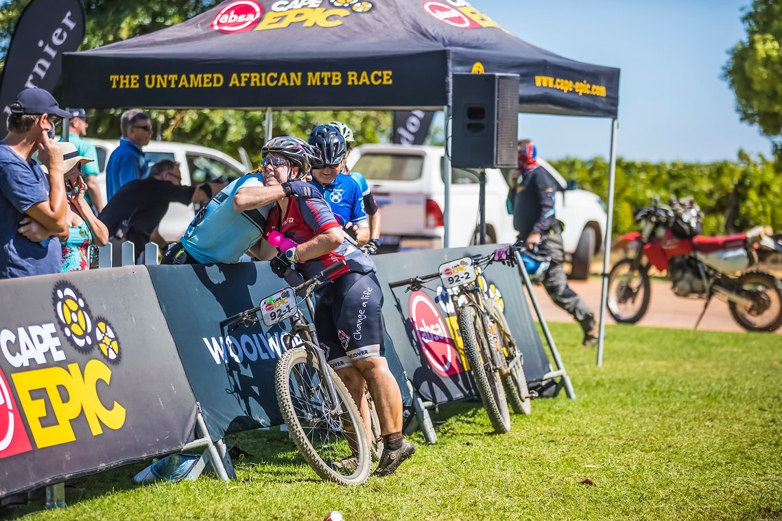 Teresa Coetzee at Water point 2 getting some encouragement during stage 1 of the 2022 Absa Cape Epic Mountain Bike stage race from Lourensford Wine Estate to Lourensford Wine Estate, South Africa on the 21st March 2022. © Dom Barnardt / Cape Epic