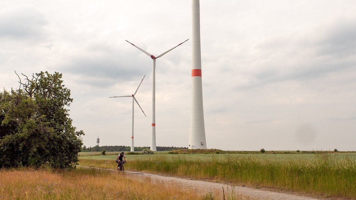 Flaches Land mit hohen Bauten. Windräder findet man hier viele und im Hintergrund erhebt sich der Funkturm "Petki"