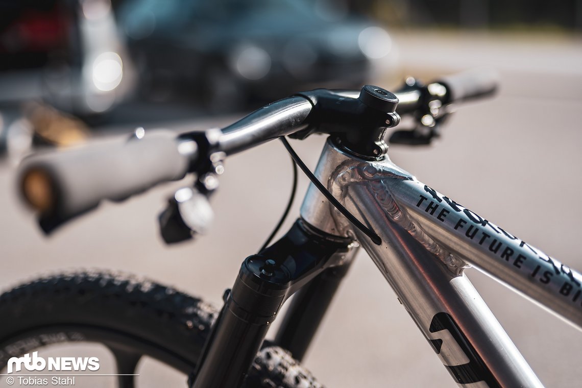 Das kurze Steuerrohr, der steil abfallende Vorbau und der Lenker mit negativem Rise sorgen dafür, dass die Position der Griffe grob der eines 29ers entspricht