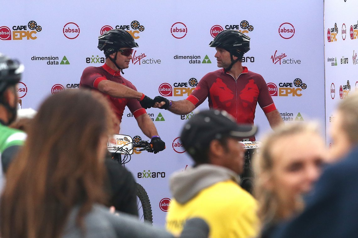 Jaco Brand and Charl Fouche fist bump before starting during the Prologue of the 2019 Absa Cape Epic Mountain Bike stage race held at the University of Cape Town in Cape Town, South Africa on the 17th March 2019.

Photo by Shaun Roy/Cape Epic

PL