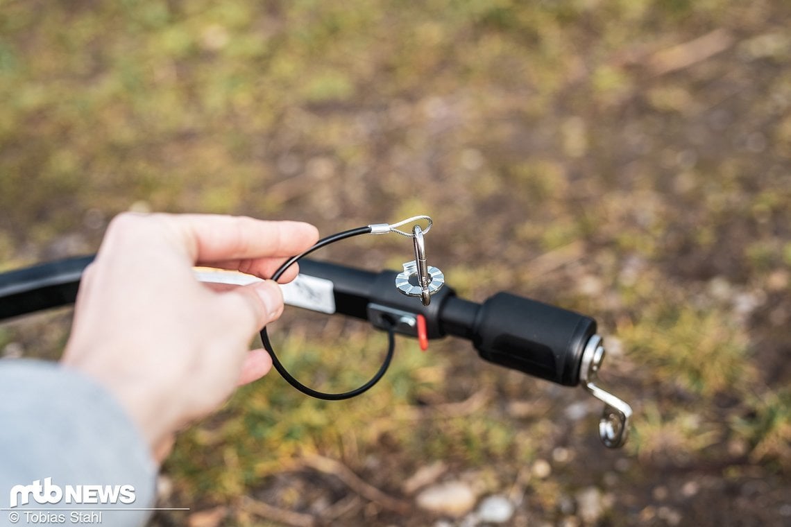 Die Fangschlaufe zur zusätzlichen Sicherung am Hinterbau des Zugfahrrades kann praktisch aus der Deichsel herausgezogen werden und wird mit einem kleinen Karabiner in die rote Öse eingehängt.