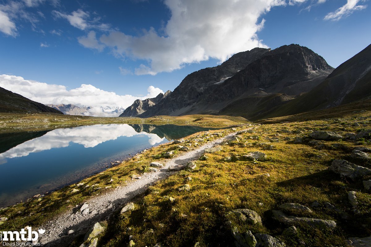 Wolkenberge türmen sich im Lej da Suvretta, Scheuchzers Wollgras säumt sein Ufer. Innehalten nach einem verdammt ausgesetzten Zickzacktrail vom Piz Nair. Wolkenberge türmen sich im Lej da Suvretta, Scheuchzers Wollgras säumt sein Ufer. Innehalten nach einem verdammt ausgesetzten Zickzacktrail vom Piz Nair.