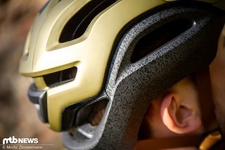 Die goldene Oberschale ist mittels Gummi-Bändern an der grauen Helm-Schale befestigt