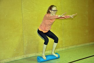 Stabilisations Übung auf einer zusammengerollten Trainingsmatte Stabilisations Übung auf einer zusammengerollten Trainingsmatte