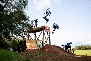 Rennen, das Bike neben sich halten, ein Salto von einem hohen Drop machen und perfekt landen Rennen, das Bike neben sich halten, ein Salto von einem hohen Drop machen und perfekt landen