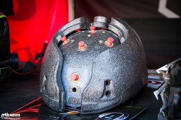 Die kleinen roten Verbindungsstücke erlauben den beiden Schalen eine Relativbewegung zueinander, die im Falle eines Sturzes Energie aufnehmen und die Momentübertragung auf den Kopf reduzieren soll Die kleinen roten Verbindungsstücke erlauben den beiden Schalen eine Relativbewegung zueinander, die im Falle eines Sturzes Energie aufnehmen und die Momentübertragung auf den Kopf reduzieren soll