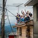 Verrückte Fans sitzen auf dem Dach eines Hauses am Streckenrand und feiern die Sportler